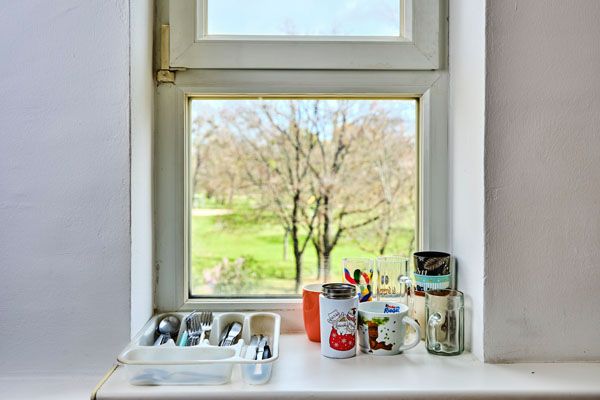 Fensterbrett mit Bestecklade und Küchenutensilien, Fenster, draußen steht ein Baum
